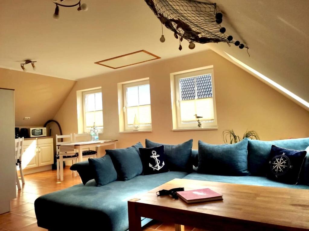 een woonkamer met een blauwe bank en een tafel bij Ferienwohnung Ostseezeit - in ruhiger Lage in Nienhagen
