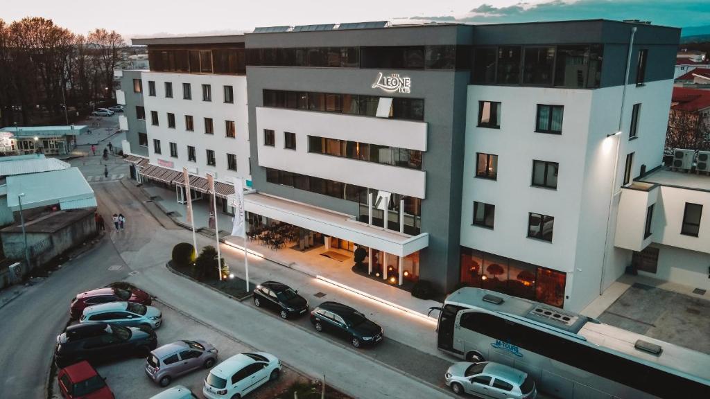 un grande edificio bianco con auto parcheggiate in un parcheggio di Hotel Leone a Međugorje