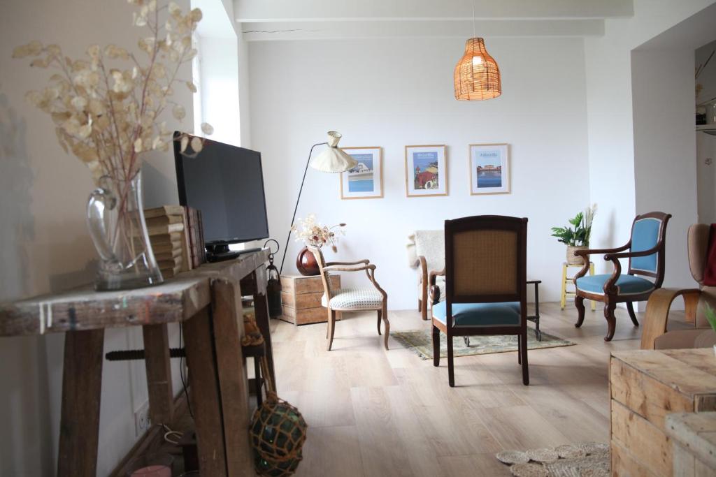 een woonkamer met stoelen en een tv op een tafel bij La Hogue au blanc in Carolles