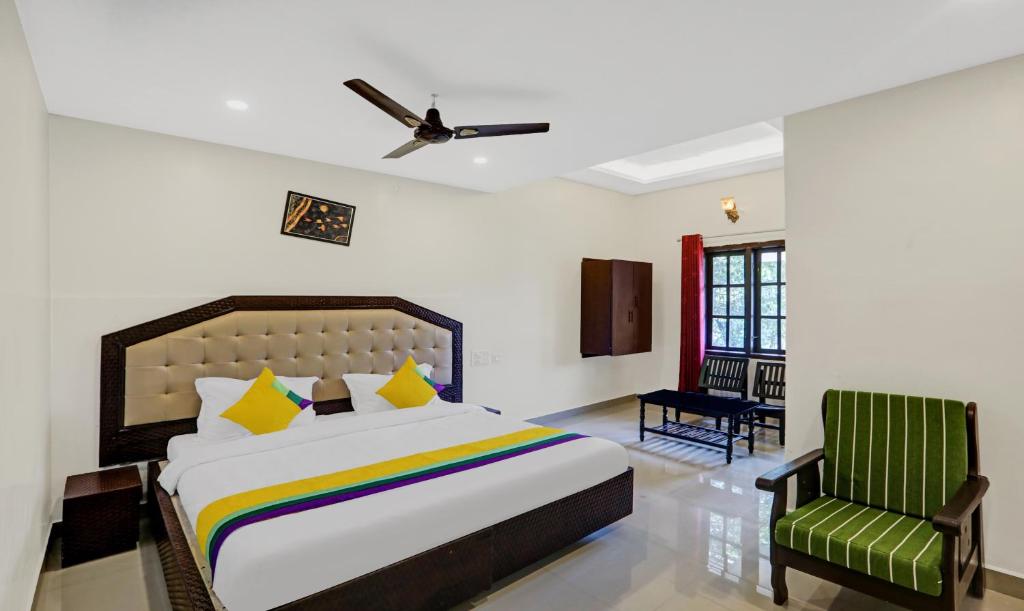 a bedroom with a bed and a green chair at Itsy By Treebo - Regalia Grand 500 Mtrs From Madikeri Fort in Madikeri