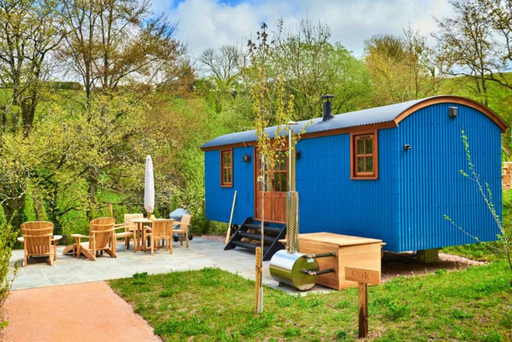 uma pequena casa azul com uma mesa e cadeiras em Finest Retreats - Maple Luxury Shepherds Hut em Dittisham