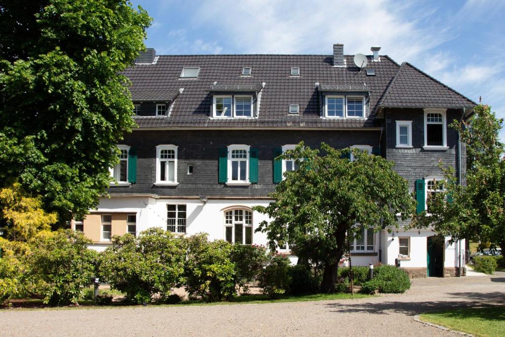 a large house with green shutters and a tree at 2T Hotel artgenossen in Lindlar