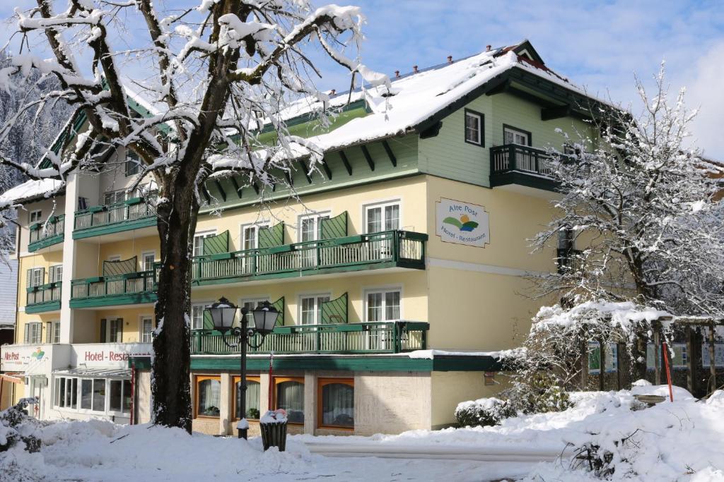 ein großes Gebäude mit Schnee auf dem Boden in der Unterkunft Hotel Alte Post in Feld am See