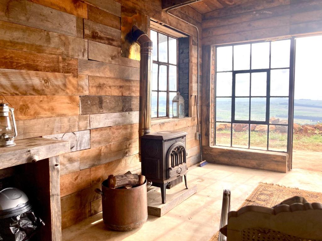 a living room with a stove in a log cabin at Rose Mountain Cottage in Nottingham Road