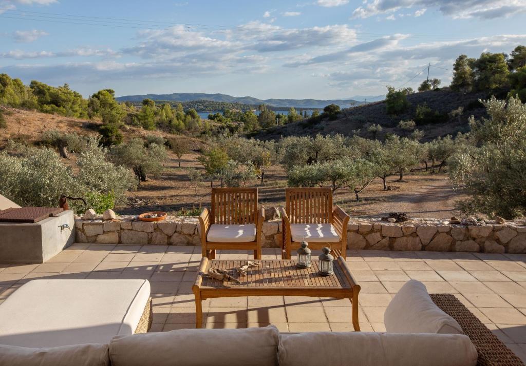 a patio with a couch and two chairs and a table at Roxanne's Olive Grove House in Kranidi