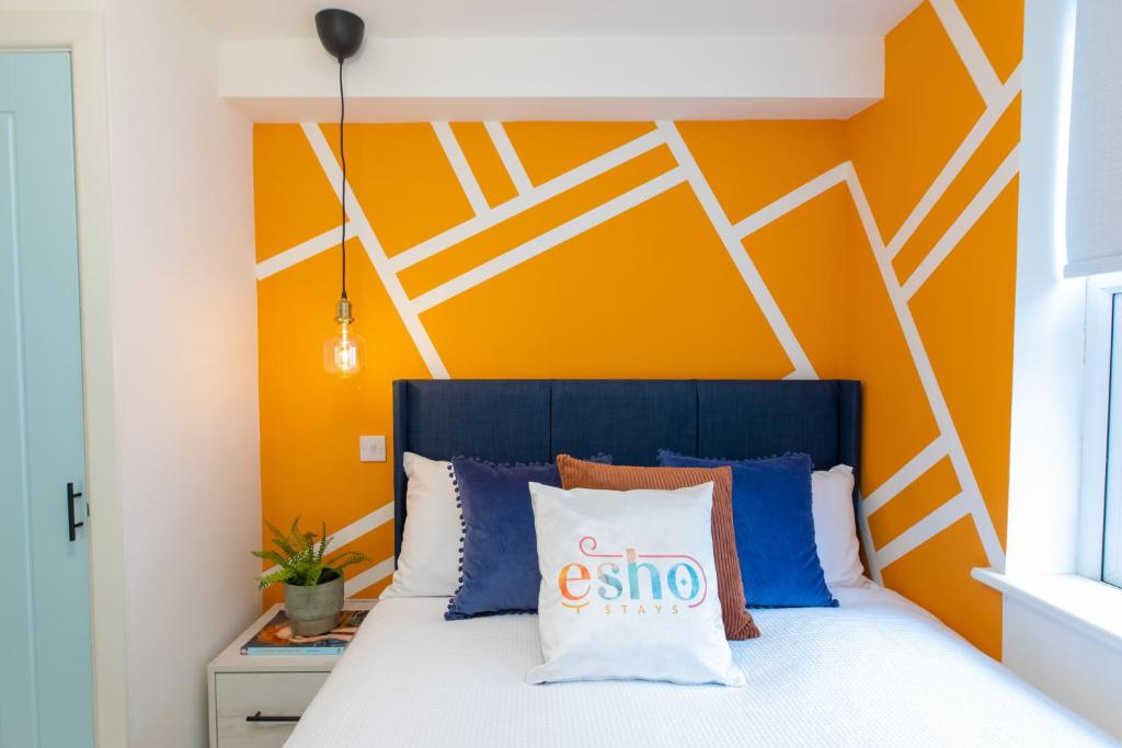 a bedroom with a bed with an orange and white wall at All BR en suite with Smart TVs 20 mins from NEC in Coventry