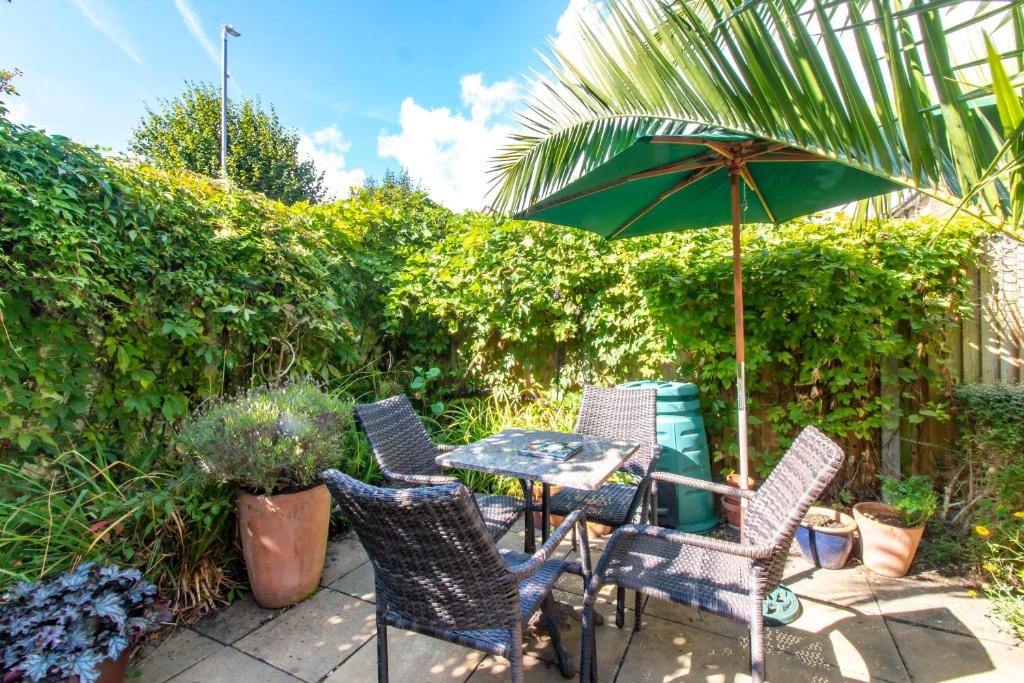 um pátio com uma mesa, cadeiras e um guarda-sol em Bradstone Garden Retreat em Folkestone