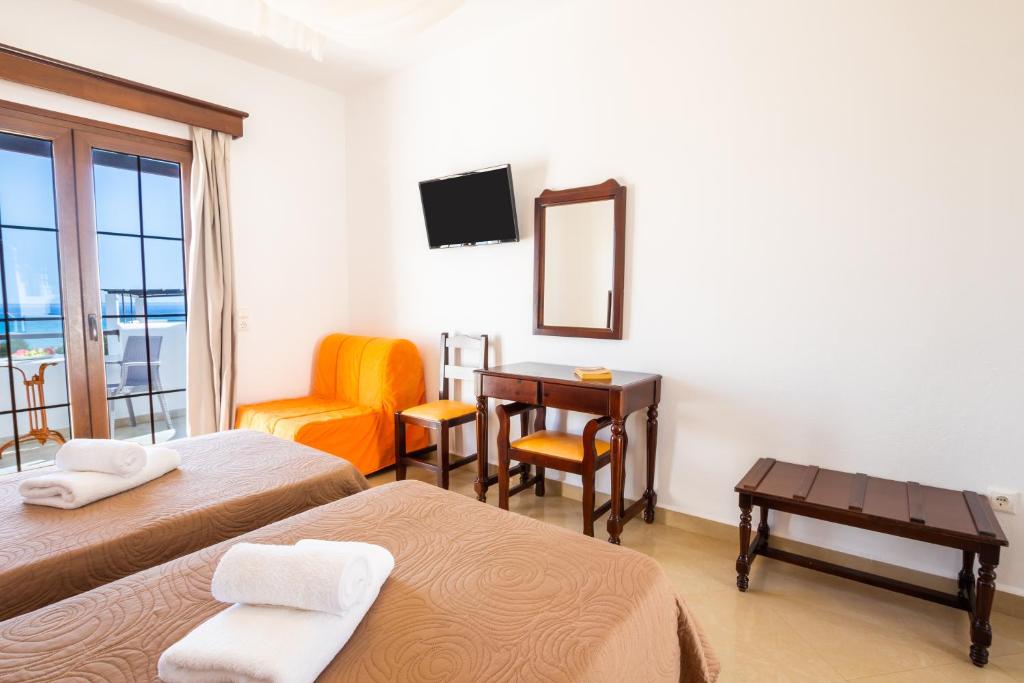 a room with two beds and a desk and a chair at Irini Hotel in Afiartis