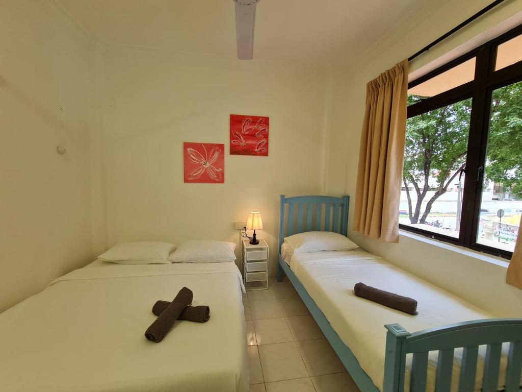 two beds in a room with two crosses on them at MG Mutiara Gurney in George Town