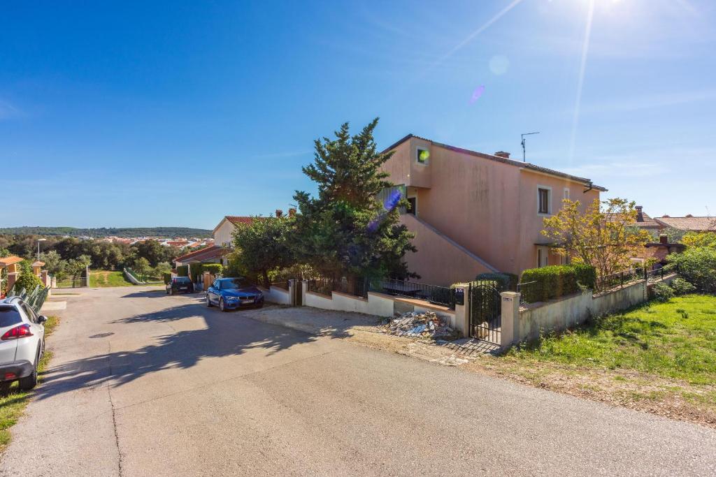 a house with a car parked on the side of a road at Apartments Davor in Banjole