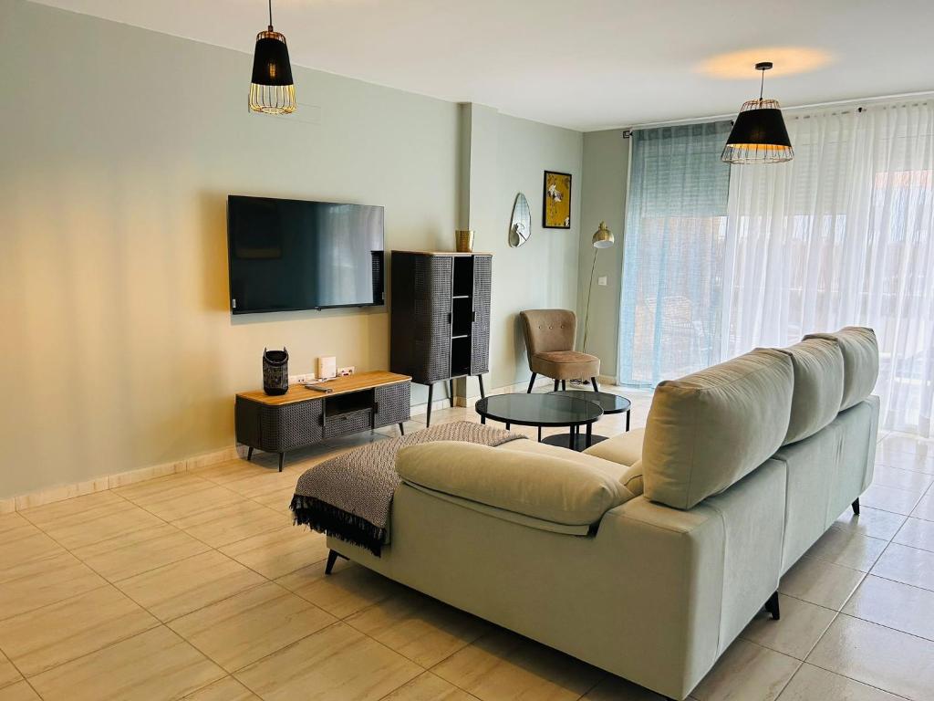uma sala de estar com um sofá e uma televisão de ecrã plano em La Maison Amarilla Golf em San Miguel de Abona