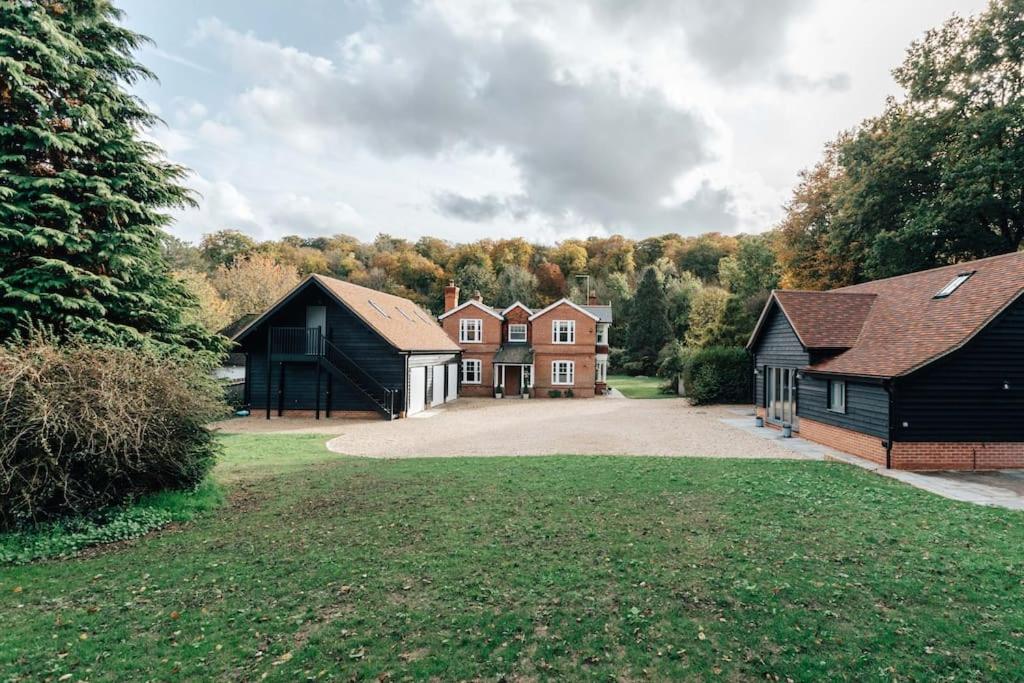 a group of houses in a field with a driveway at Woodvale - Sleeps 20 in Harpsden