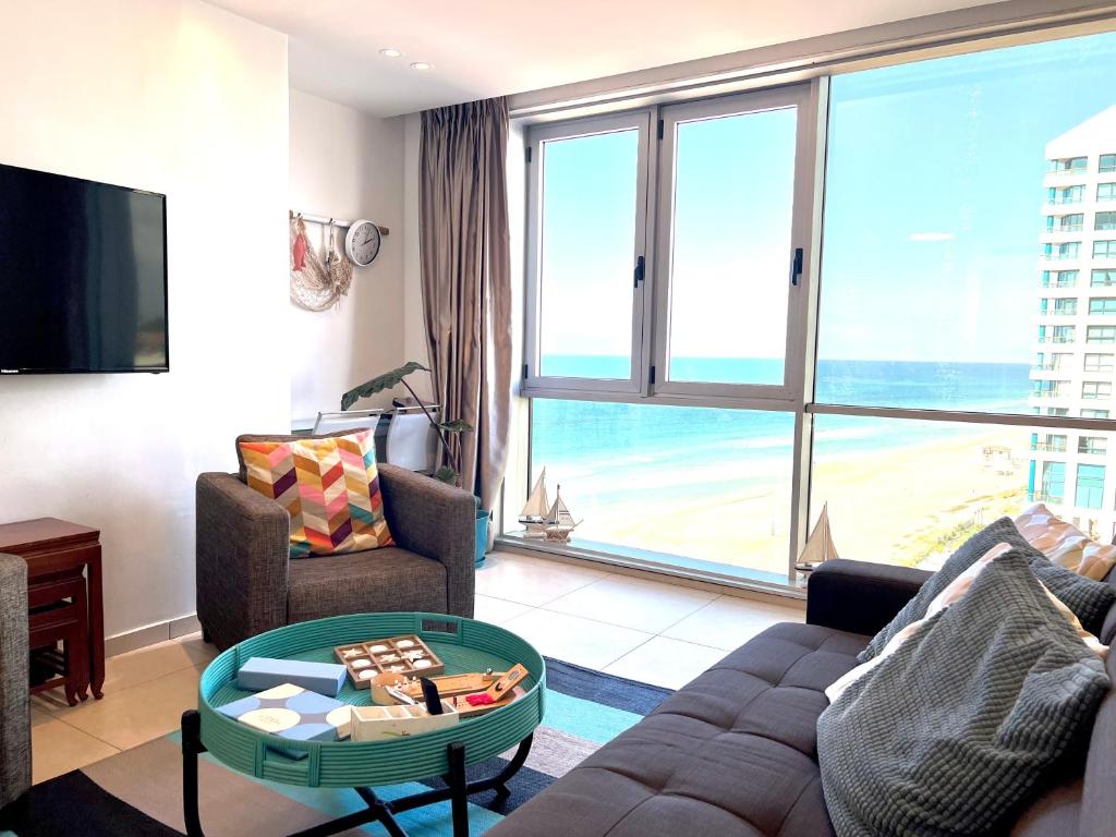 een woonkamer met een bank en een tafel bij Beach Apartment- breathtaking views with bomb shelter in Herzelia 