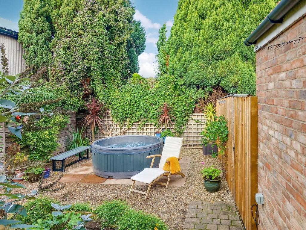 a garden with a hot tub and two chairs and a fence at The Old Antique Shop in Malton