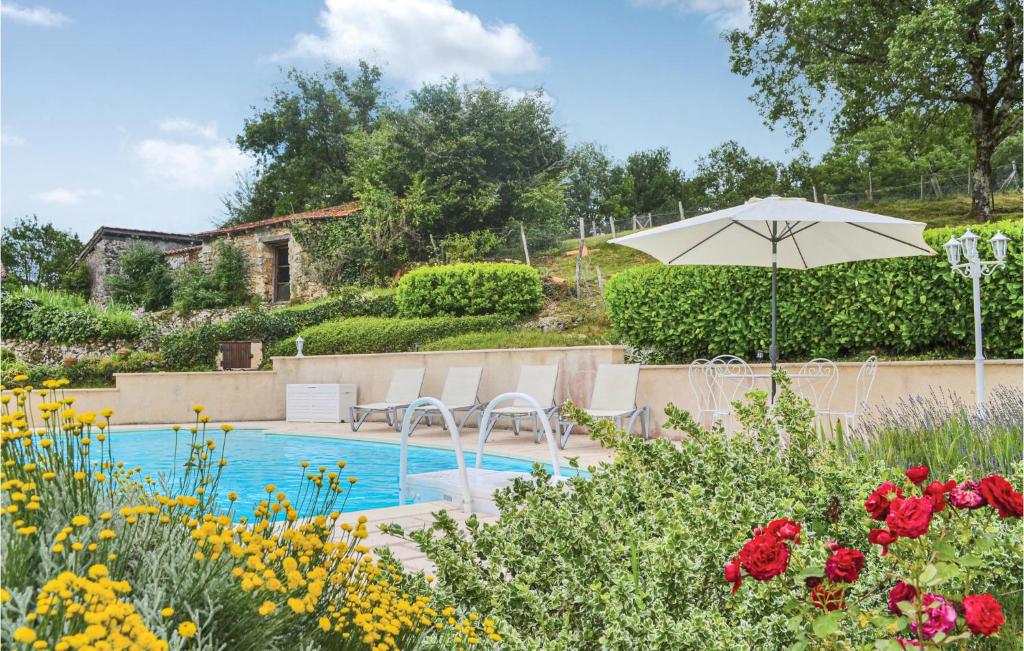 una piscina con sombrilla, sillas y flores en 1 Bedroom Gorgeous Home In Brantome, en Brantôme