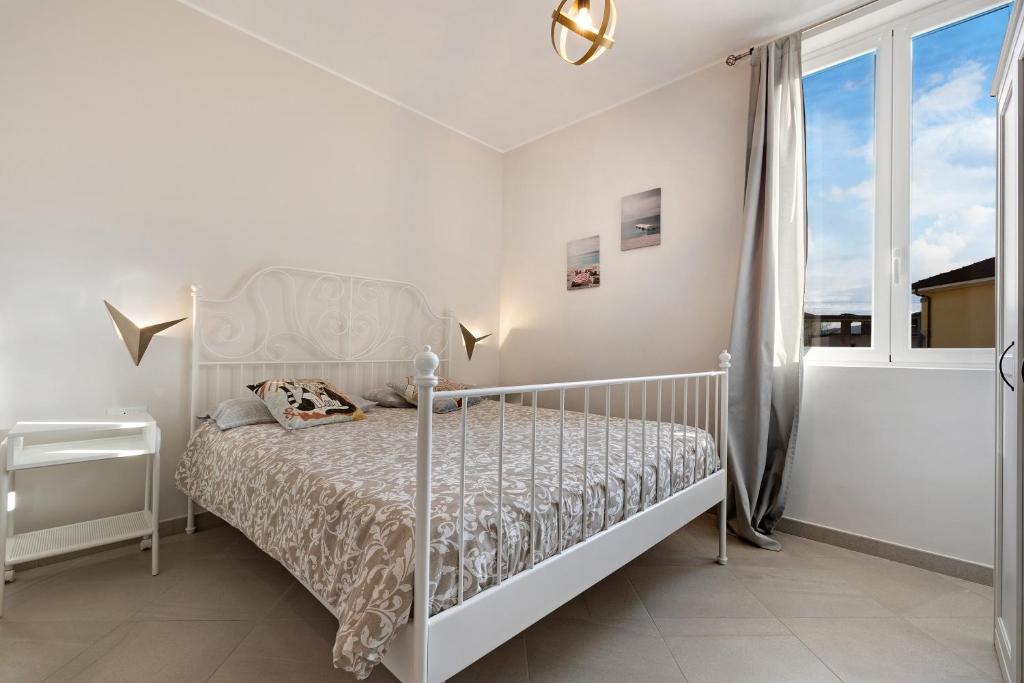 een witte slaapkamer met een bed en een raam bij 4 Passi Mare 2 in Finale Ligure