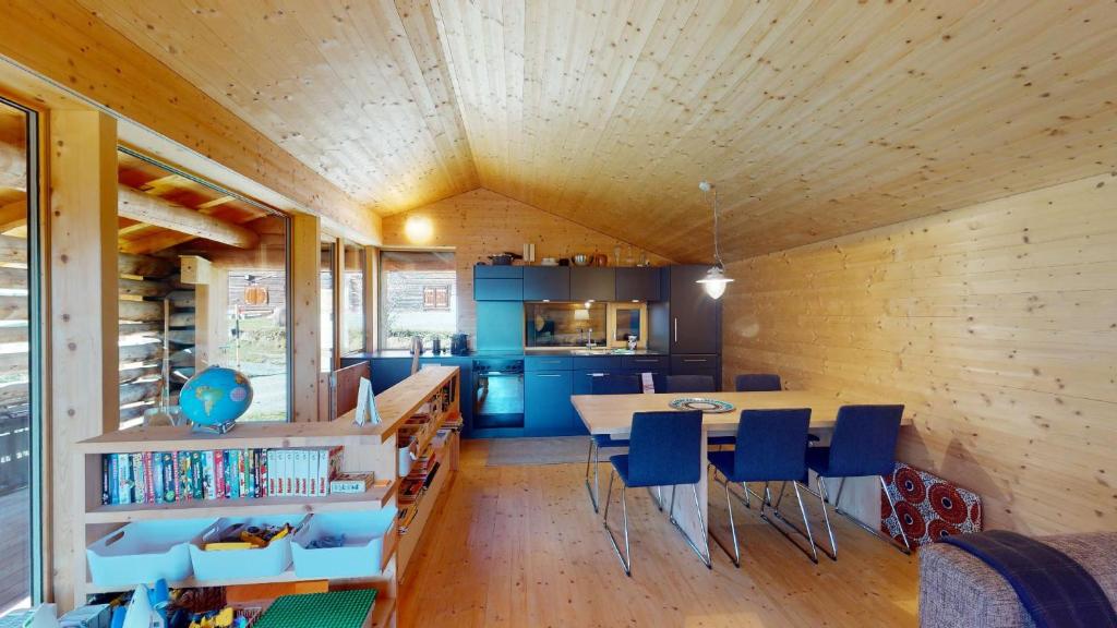 a kitchen and dining room with a wooden ceiling at Mountain Cabin Mutten-Graubünden in Mutten