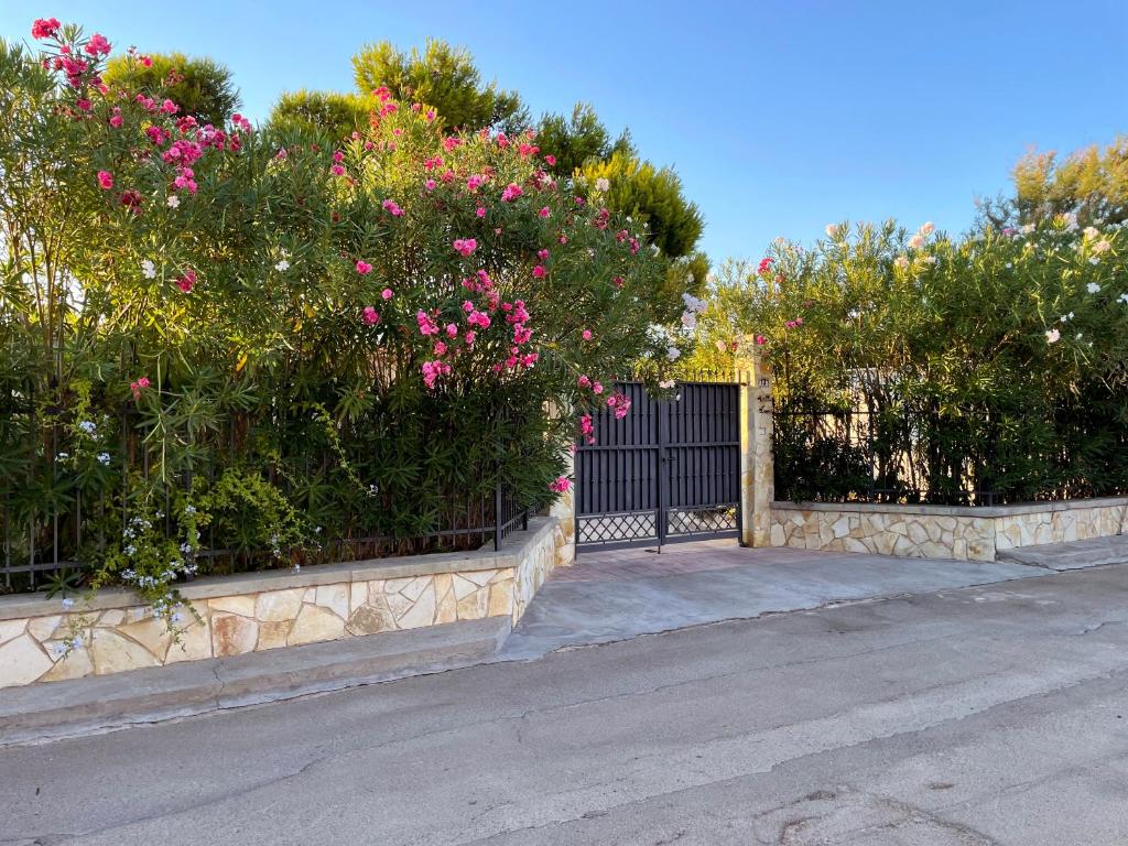 a gate with a bunch of pink flowers and bushes at Villa Luce in Torre rinalda