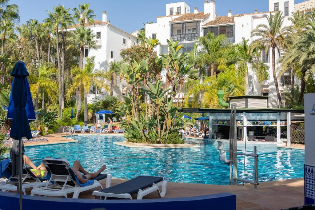 een zwembad in een resort met 2 personen in ligstoelen bij SF Marbella Luxury Beach Apartment - Jardines de las Golondrinas in Marbella