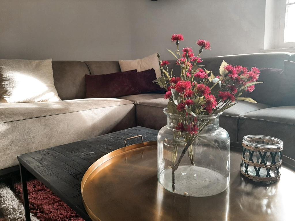 a vase with flowers on a table in a living room at Edle Altbauwohnung trifft oberbayrisches Bergidyll in Bayrischzell