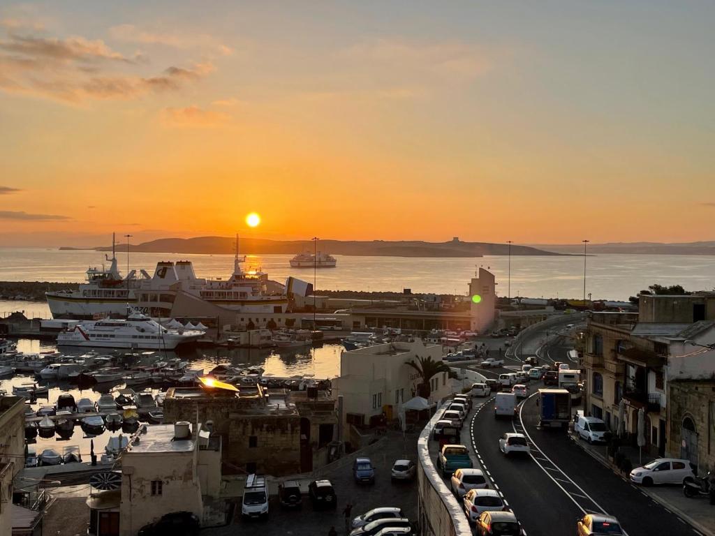 a sunset over a city with a lot of cars at Seafront Apartment with Balcony Overlooking Marina in Għajnsielem
