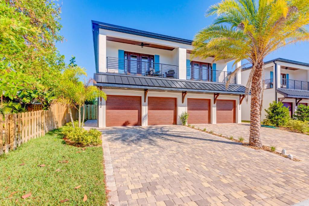 a house with two garage doors and a palm tree at Sea Flamingo in Cape Canaveral