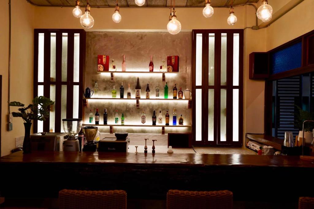 A warmly lit bar with illuminated shelves of bottles and a polished counter.