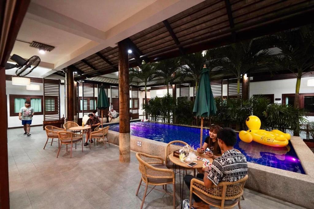 A covered poolside dining area with guests seated beside a narrow courtyard pool.