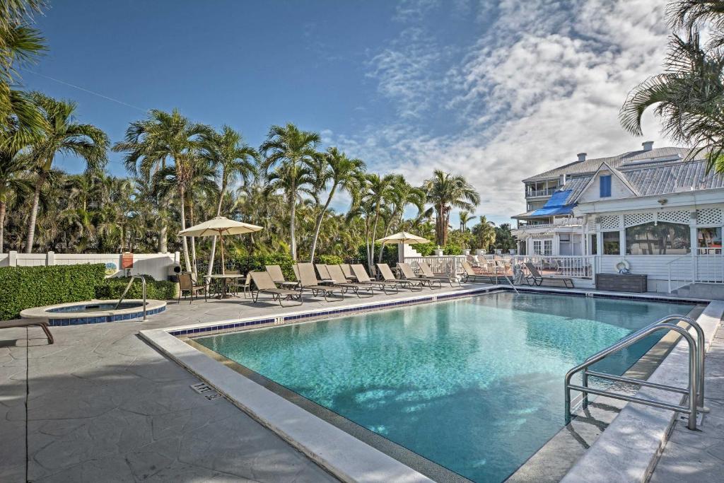 a swimming pool with chairs and a house at Marco Island Condo with Shared Pool and Hot Tub! in Marco Island