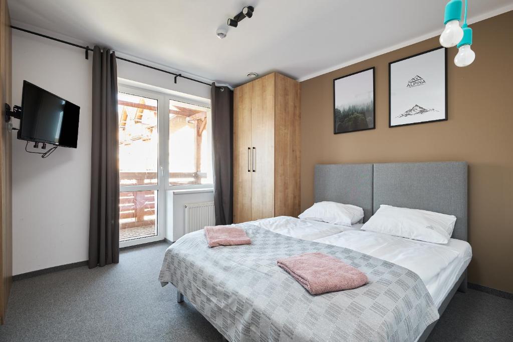 a bedroom with a large bed with a tv on the wall at Villa Alpina in Szklarska Poręba