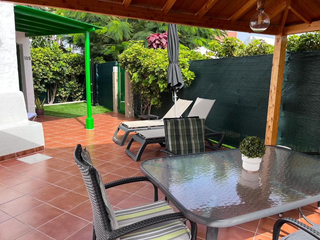 a patio with a table and chairs and an umbrella at Ahtha Green Bungalow Maspalomas in San Bartolomé de Tirajana