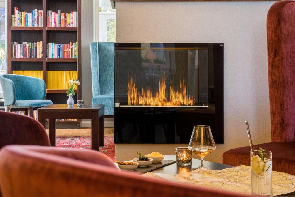 - un salon avec une cheminée, une table et des chaises dans l'établissement Logis Hotel QUARTIER 5, Sächsische Schweiz, mit Restaurant, Café & Bar, à Gohrisch