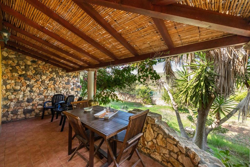 a patio with a wooden table and chairs under a wooden roof at Villa Maladroxia in Maladroscia