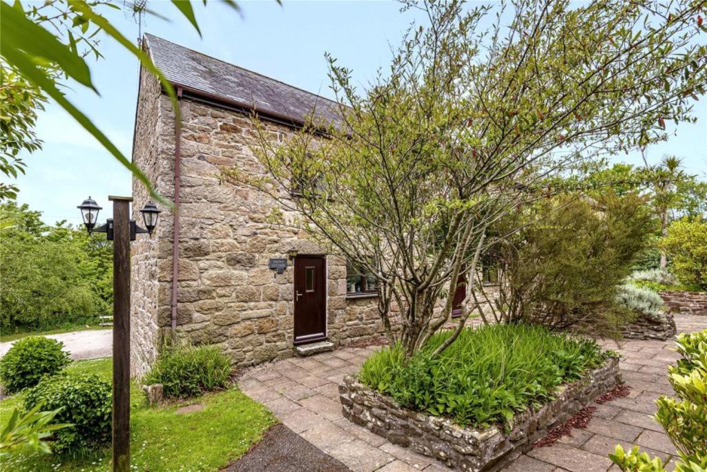 a stone cottage with a tree in front of it at Saddle Cottage in Penzance