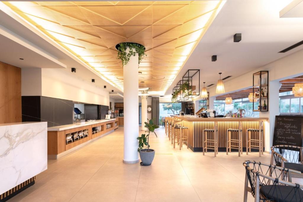 a restaurant with a bar and a dining area at Malena Hotel & Suites - Adults Only by Omilos Hotels in Amoudara Herakliou