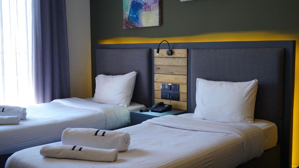 Habitación de hotel con 2 camas y toallas. en Aitch Boutique Hotel - an LIH Hotel en Madaba