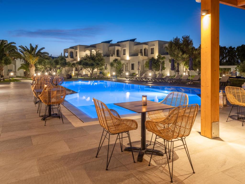 a patio with a table and chairs next to a pool at Malena Hotel & Suites - Adults Only by Omilos Hotels in Amoudara Herakliou
