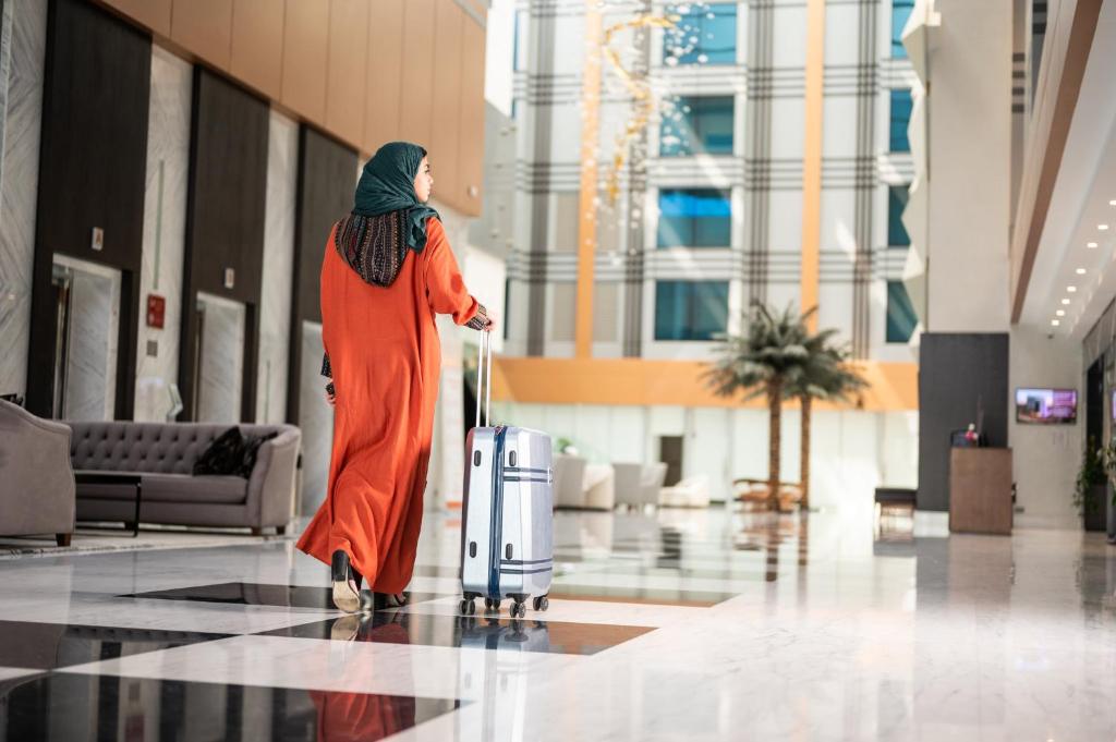a woman walking through a building with her luggage at Crowne Plaza Hotel Riyadh Minhal, an IHG Hotel in Riyadh