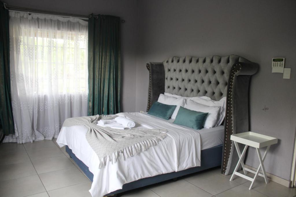 a bedroom with a bed with blue and white pillows at Sable Holiday Home in Hazyview