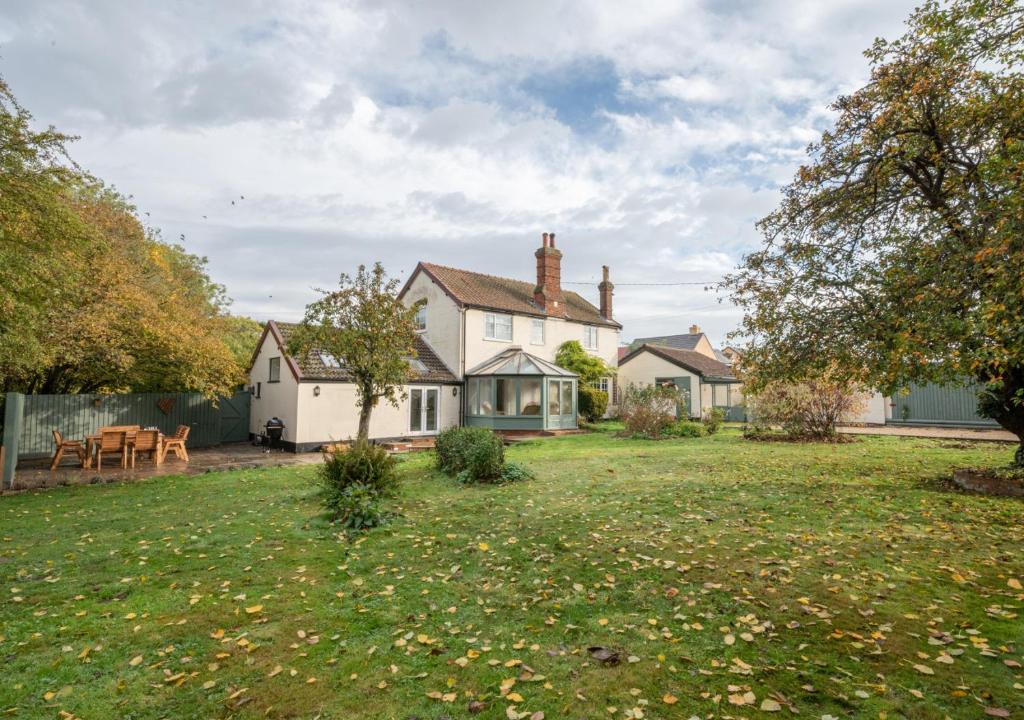 a house with a yard with a table in front of it at CowPasture Cottage in Felixstowe