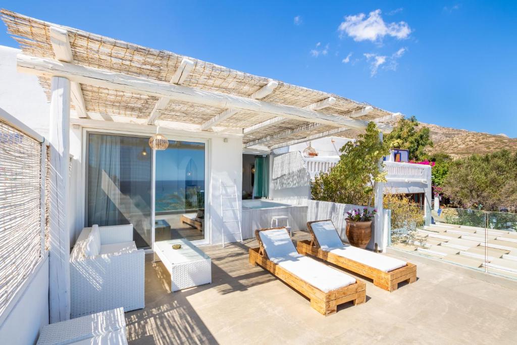 a patio with two lounge chairs and a pergola at Poseidon Blue Gastronomy Hotel in Afiartis