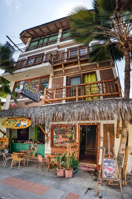 a building with a straw roof and a restaurant at Hotel Boutique Hurvínek in Montañita