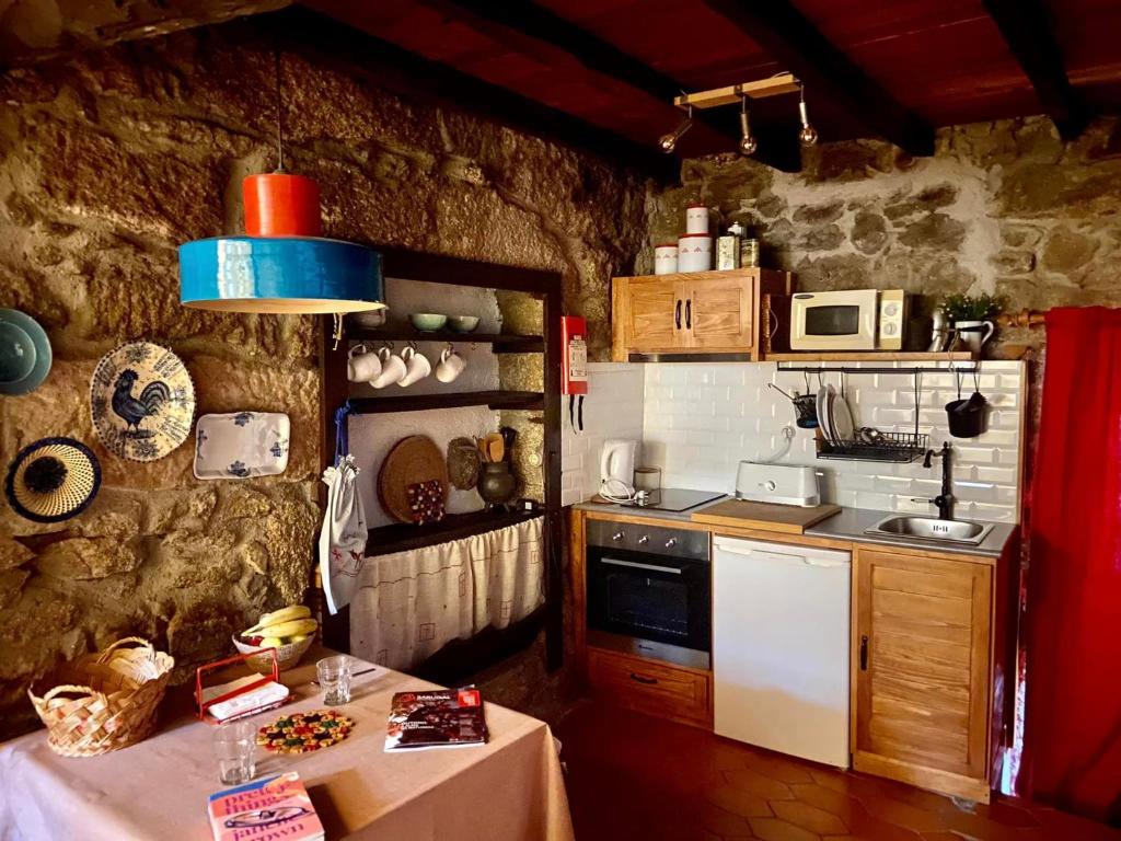 cocina con mesa y fogones horno superior en Casa das 5 Cruzes dentro da muralha, en Sortelha