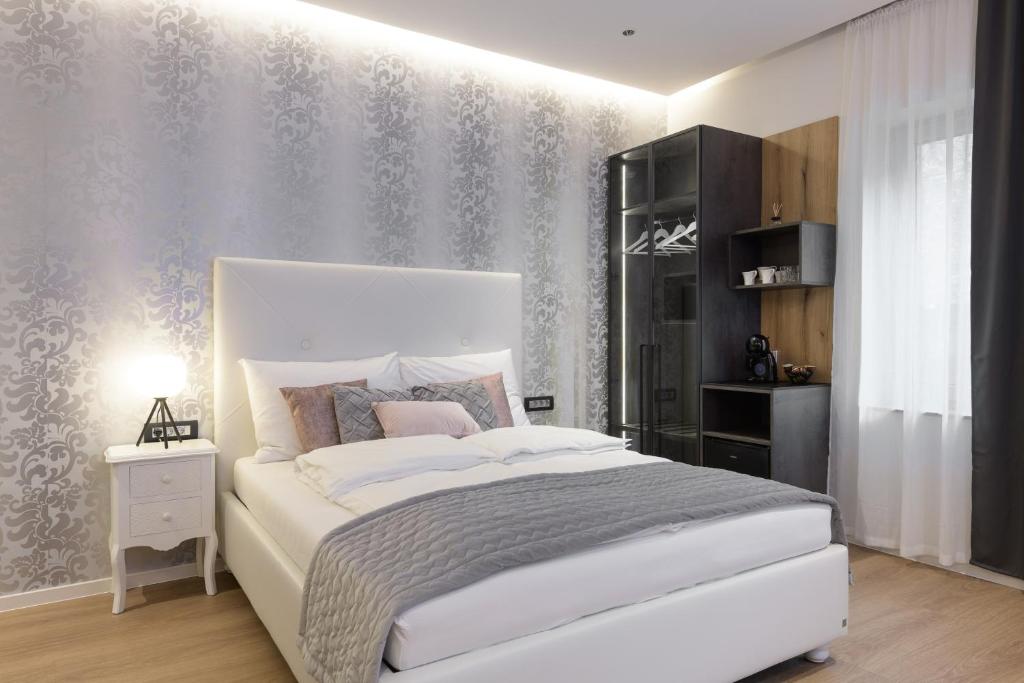 a bedroom with a large white bed and a wall at ROYAL SUITE, Ljubljana in Ljubljana