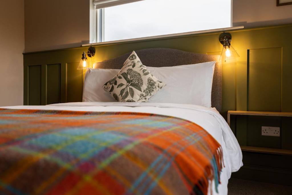 - un lit avec une couverture et des oreillers colorés dans l'établissement Aiteall Boutique Accommodation, à Liscannor
