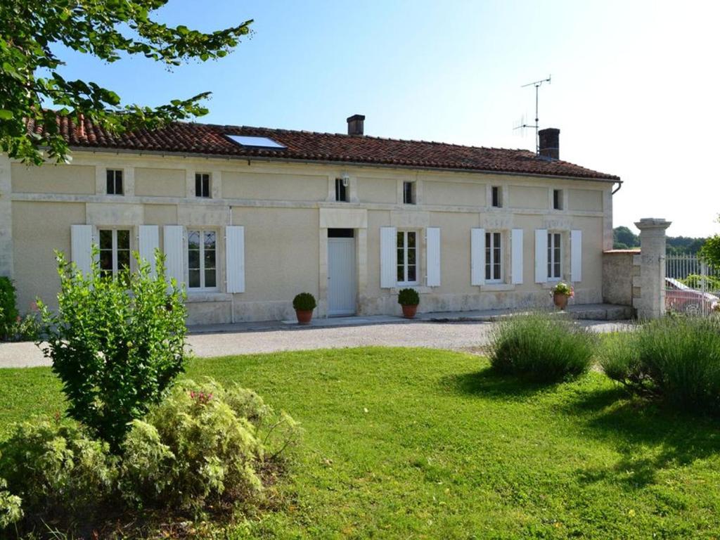 a large white house with a yard in front of it at Gîte viticole avec jardin clos, terrasse, jeux et visites de distillerie en Charente - FR-1-653-30 in Lignières-Sonneville