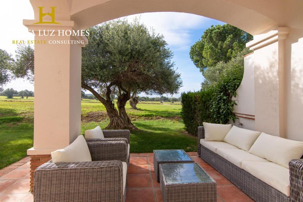 eine Terrasse mit einem Sofa, Stühlen und einem Baum in der Unterkunft Arcos Garden campo de golf fairway in Vallejas