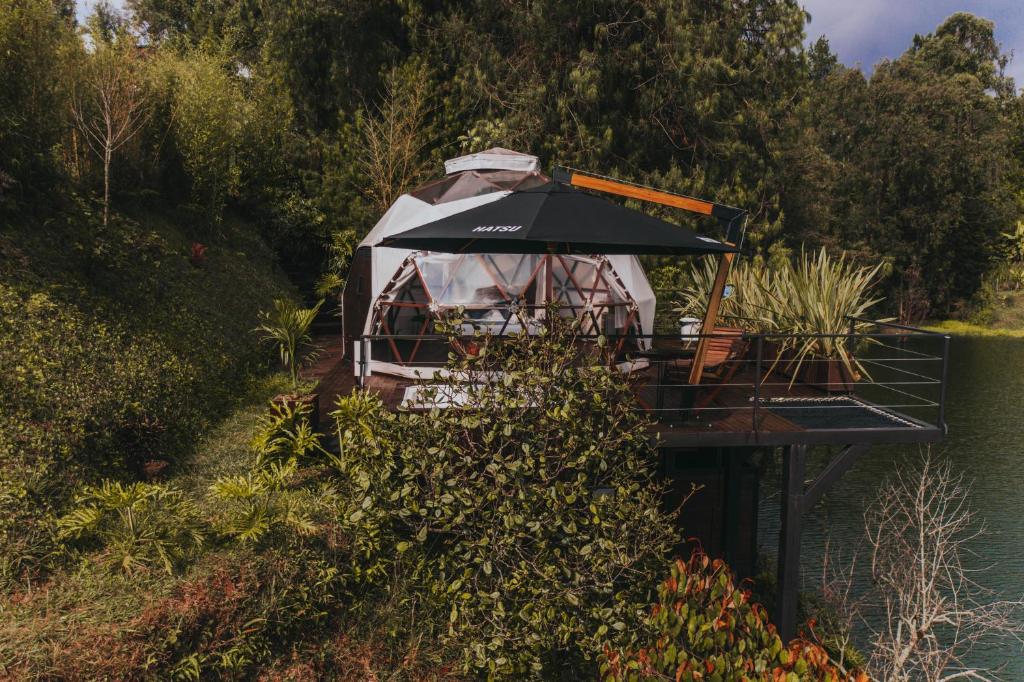 a tent sitting on a dock with an umbrella at Domus Glamping in Guatapé