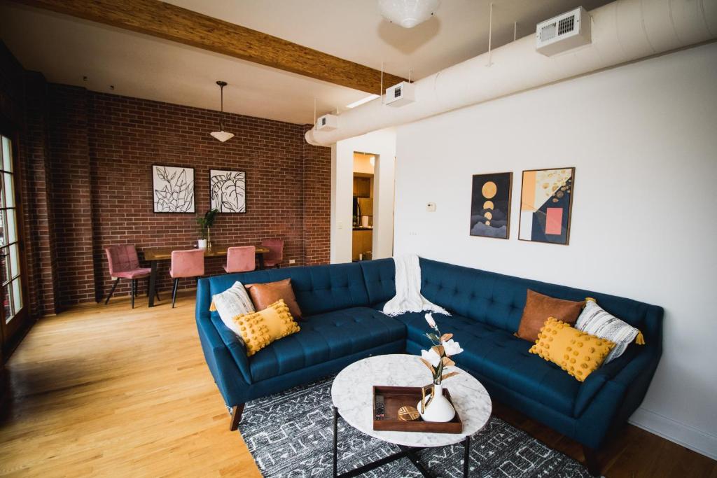 a living room with a blue couch and a table at Spacious Loft Over Coffee Shop - Romantic Downtown Escape in Greeley