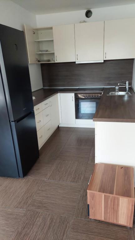 a kitchen with a black refrigerator and white cabinets at Apartma Samo 3 in Kranj